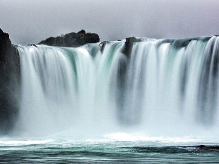 Woda wodospadu Godafoss spadająca z ciemnej skalnej półki