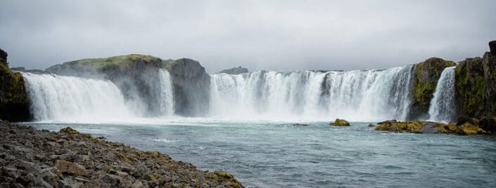Panorama wodospadu Godafoss z brzegu rzeki poniżej progu
