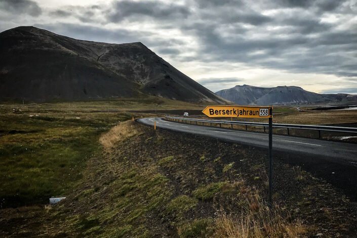 The yellow Berserkjahraun 558 road sign at the turn-off from road 54, with a red-brown crater behind it