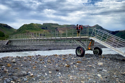 person crossing a mobile mountain footbridge