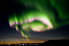 Vivid spiral multicolour aurora borealis lighting up the sky over a road on Iceland's south shore