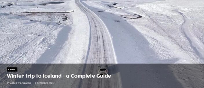 White car driving on a snow-covered Ring Road through a completely white winter landscape in Iceland