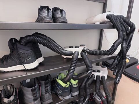 Shoe rack with electric shoe dryer at Midgard Basecamp hostel entrance, with wet hiking boots drying